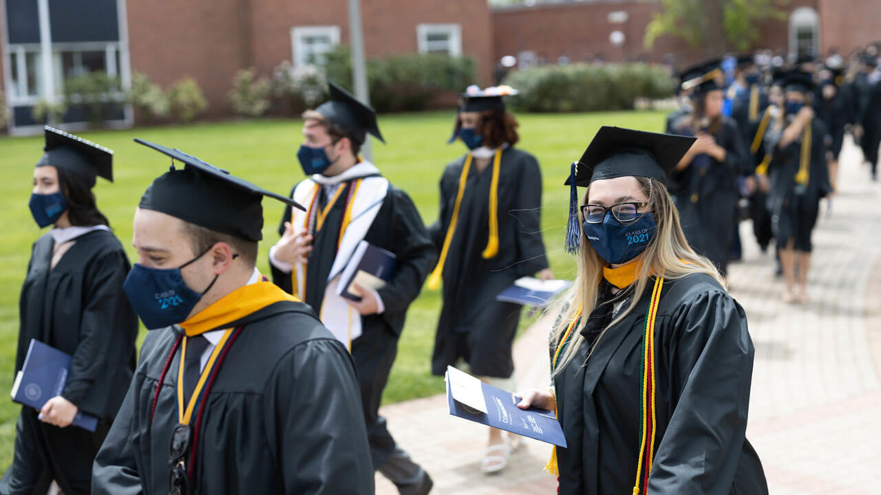 Dozens of students walk down the quad for the Commecement ceremony