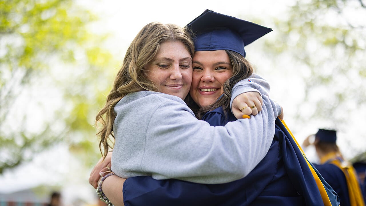 graduate hugs loved one