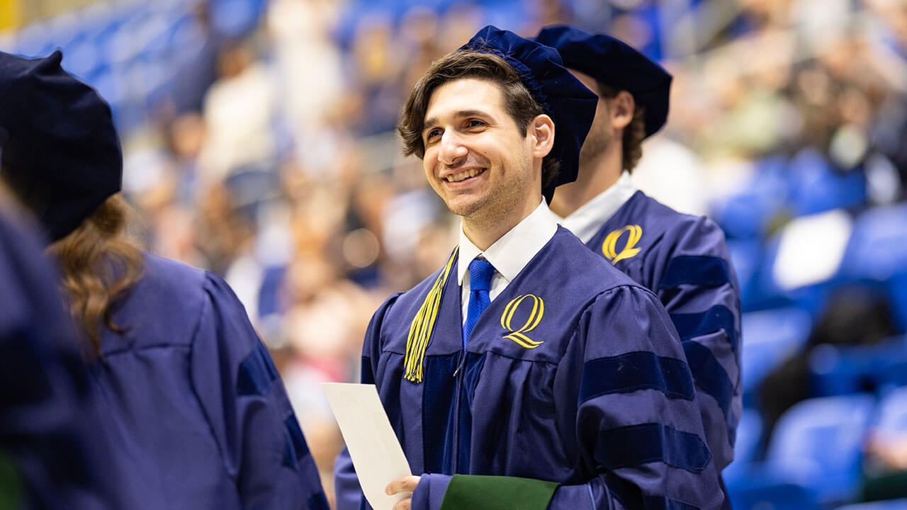 graduate smiles as they line up for the stage