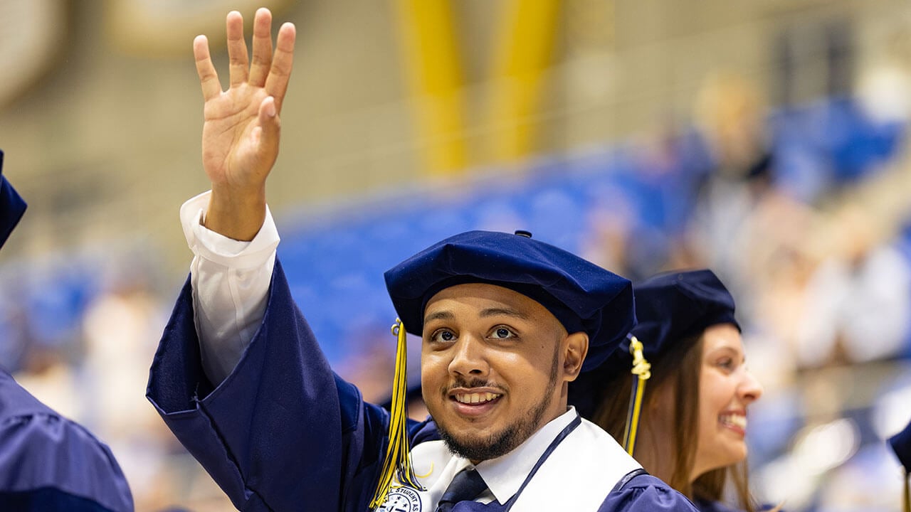 graduate waves to the audience
