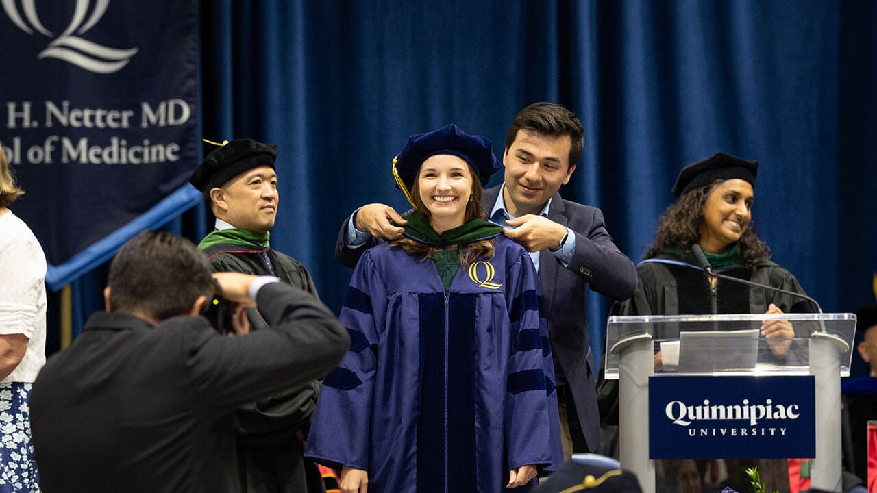 graduate receives hood from a loved one