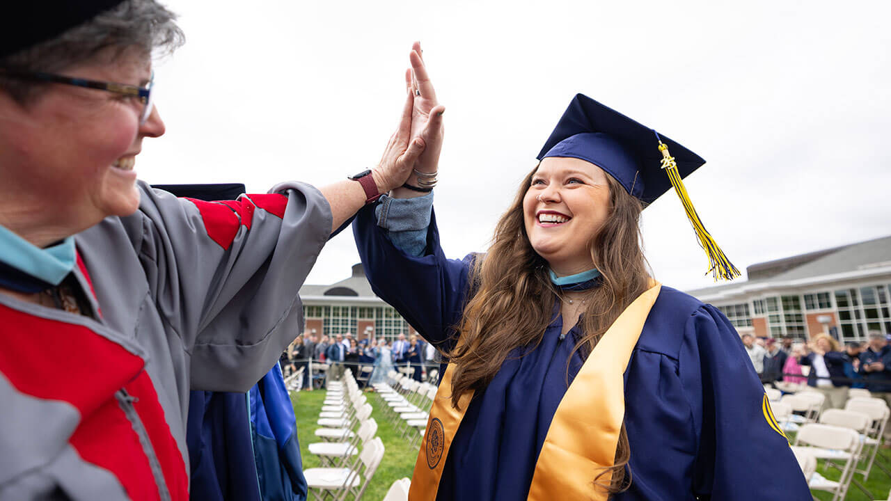 graduate high fives with Cindy Kern, Associate Teaching Professor of Science Education