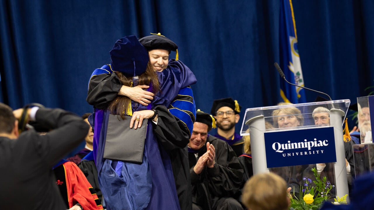 Student hugs their professor as they receive their diploma.