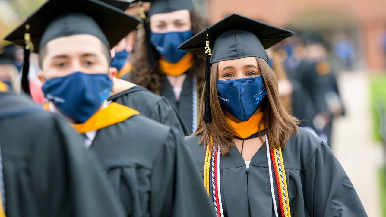 Two grads smile as they process into the Commencement ceremony