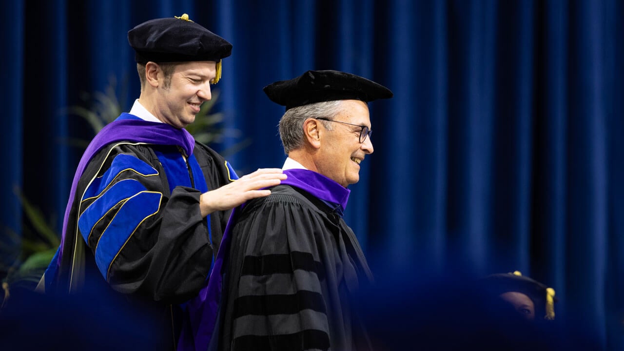 Dean Brian Gallinii hoods Craig N. McLean, JD '93.