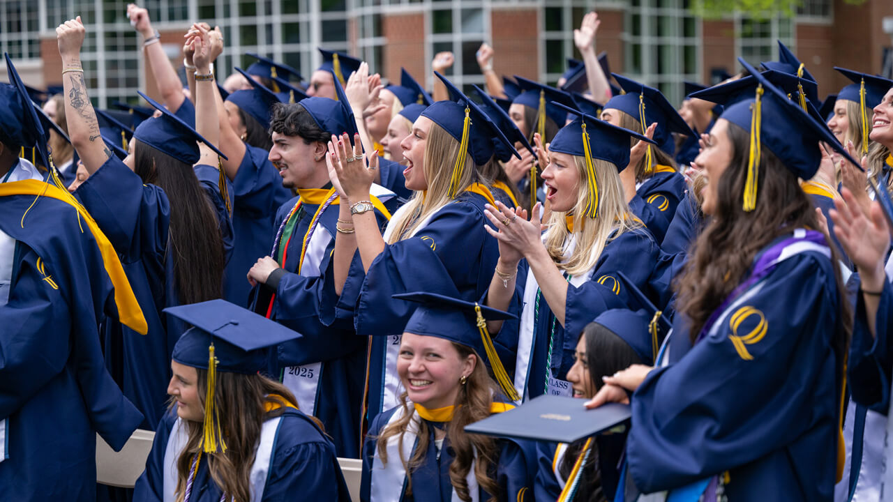 A crowd of graduates in caps and gowns cheering