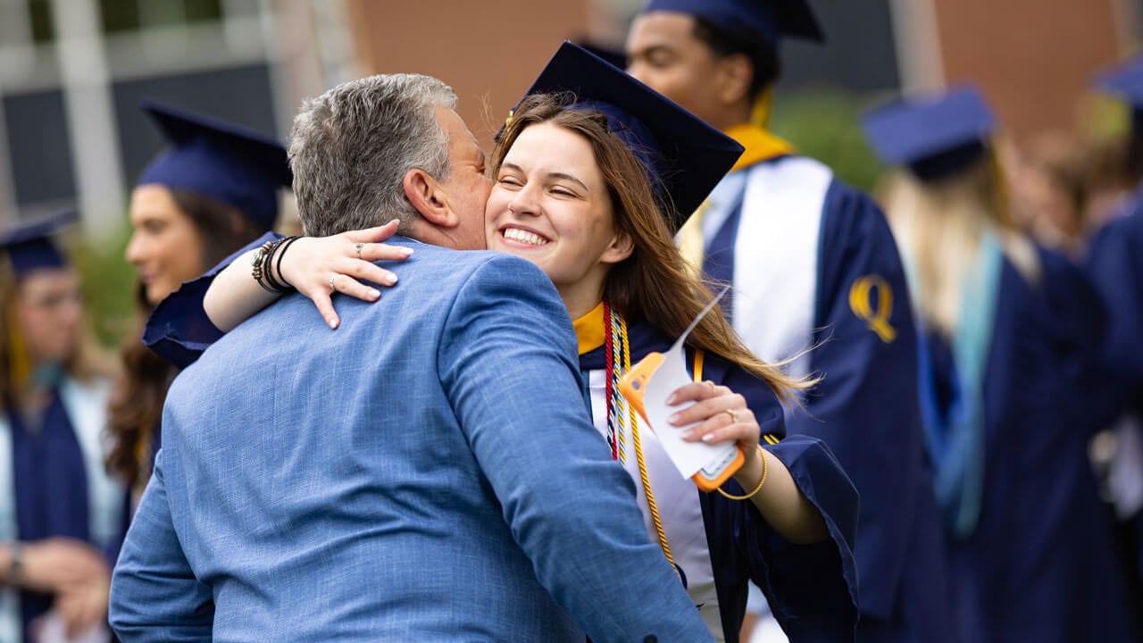Graduate enthusiastically hugs loved one