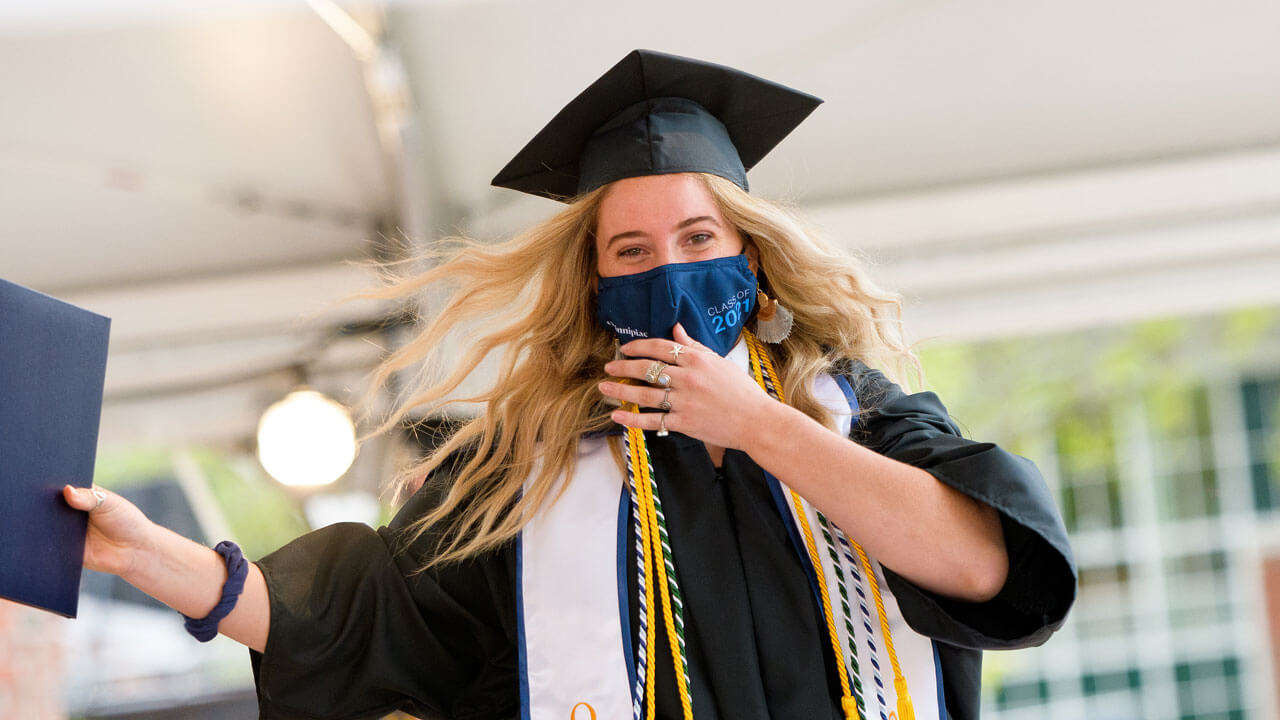 A graduate holds up her diploma cover as she walks across the stage