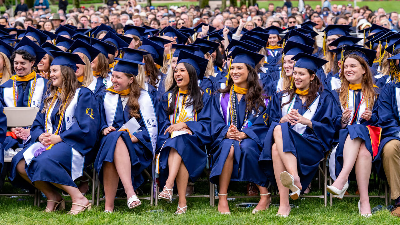 Graduating students sit and smile during speeches