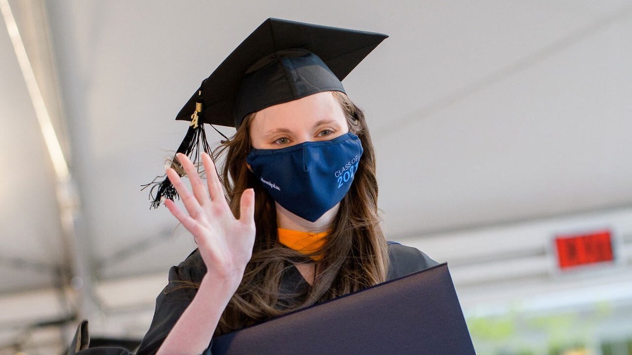 Kim Shepherd waves as she walks across the Commencement stage