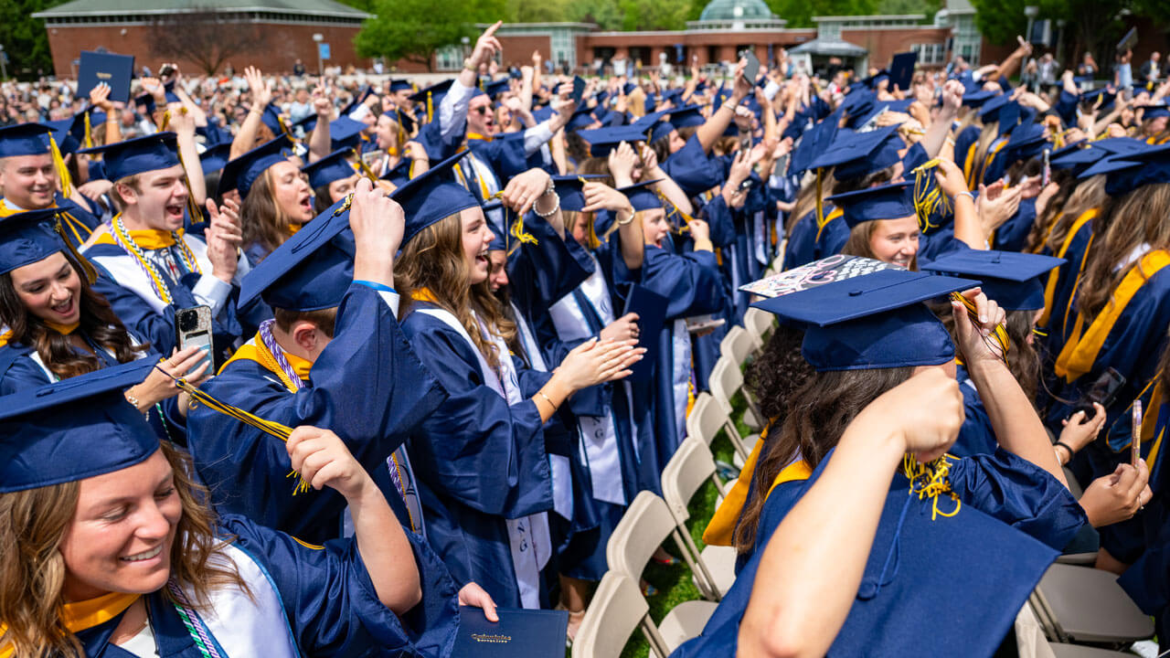 Crowd of graduating students cheering on the quad