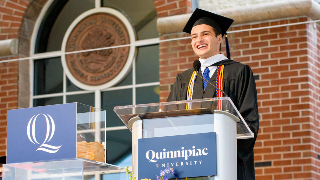 Tyler McNeill speaks at a podium on the library steps