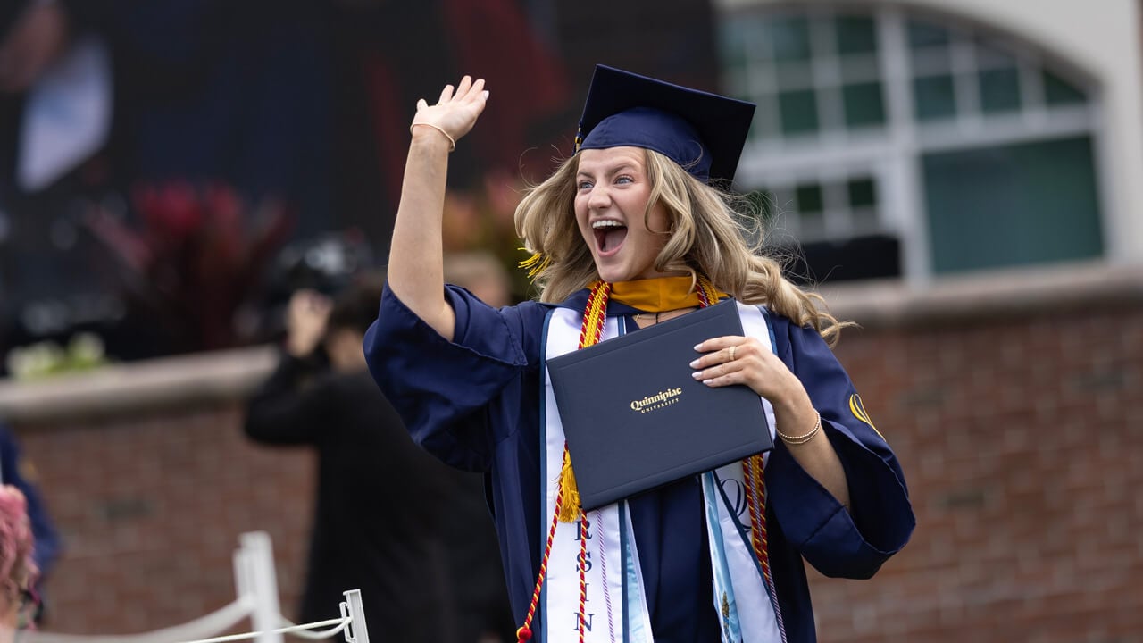 Female graduate posing excitedly with diploma cover