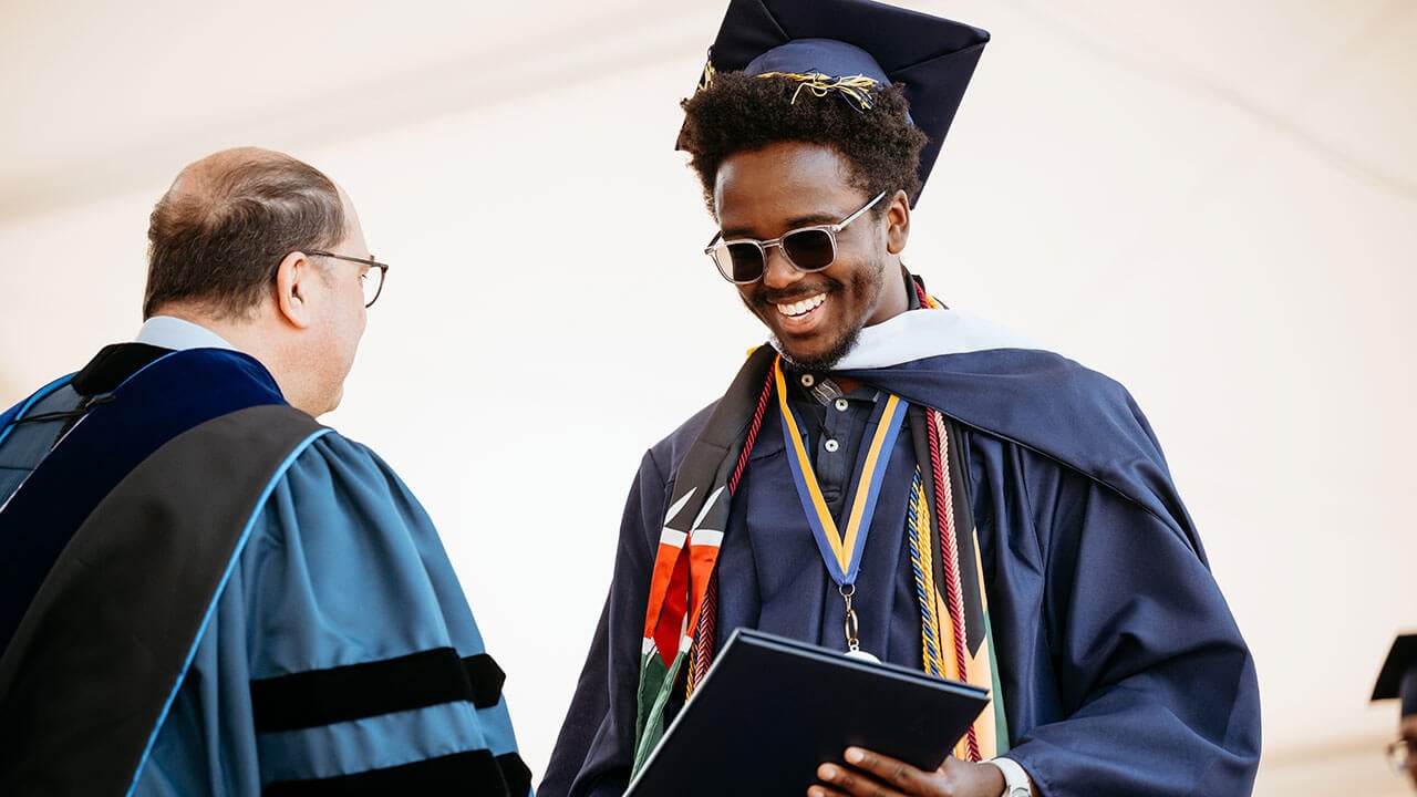 A graduate smiling after getting his diploma