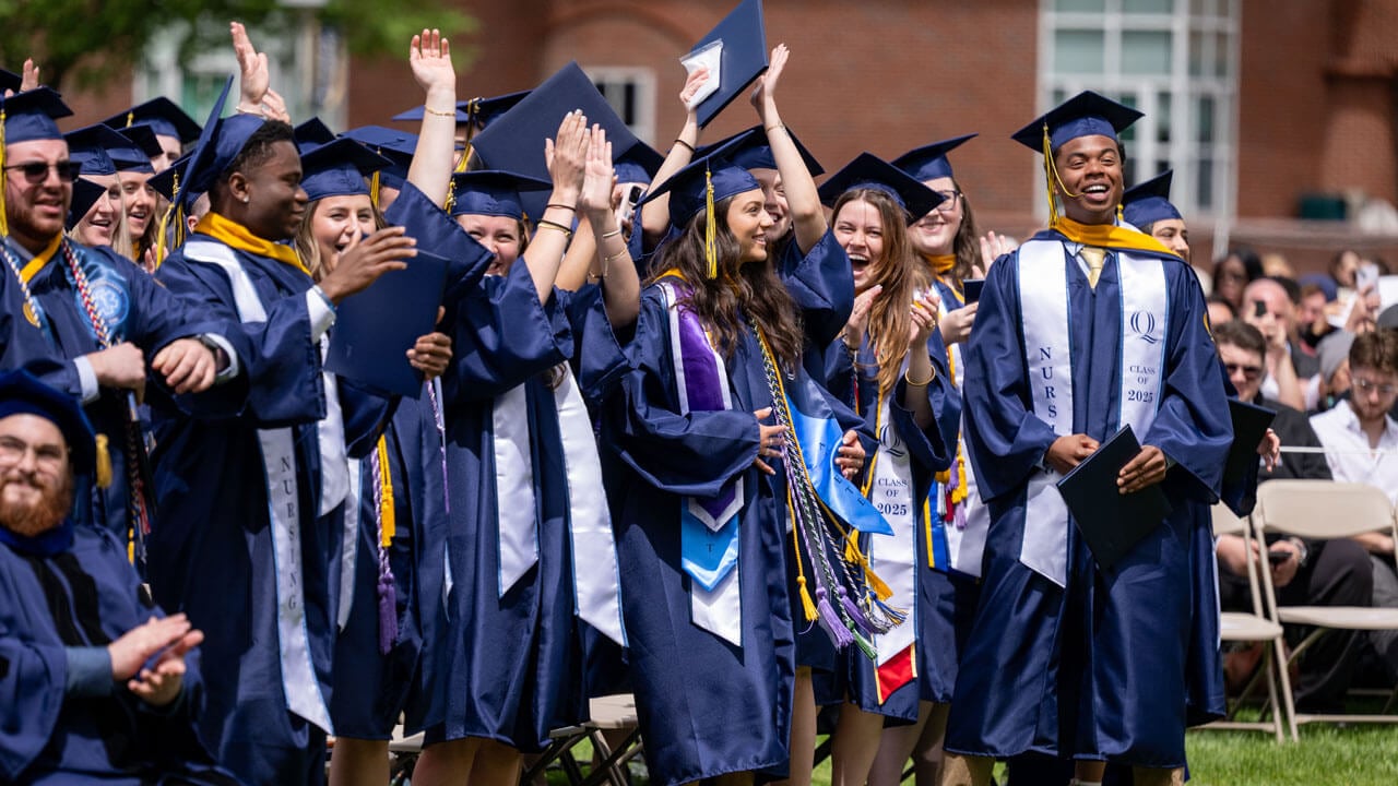Graduates clap and cheer from the crowd.