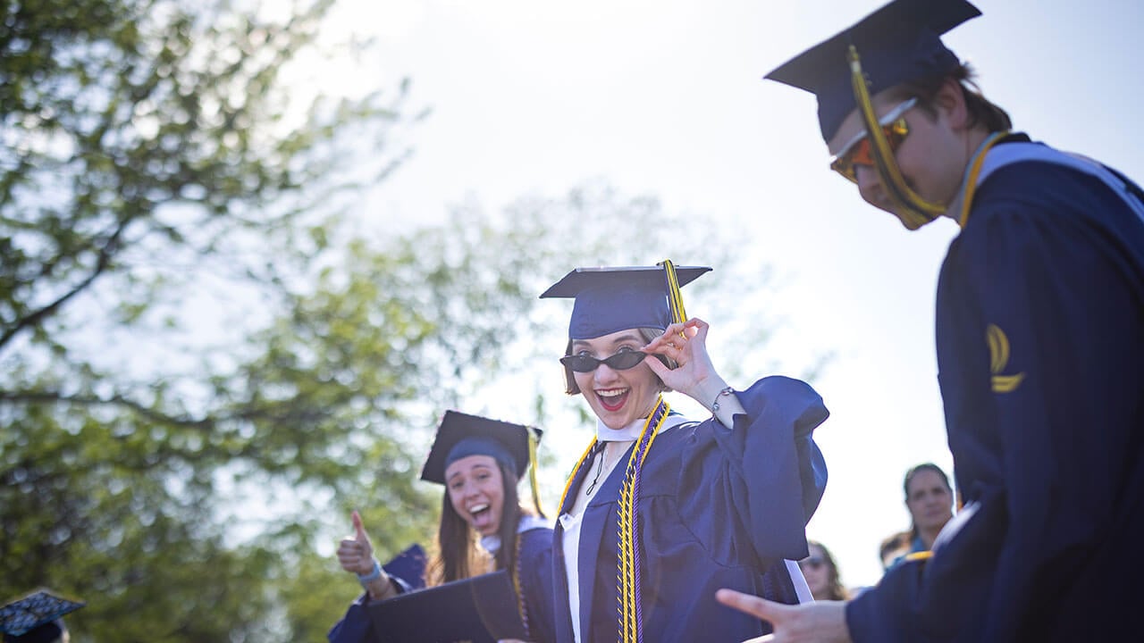 graduate pulls sunglasses for the picture