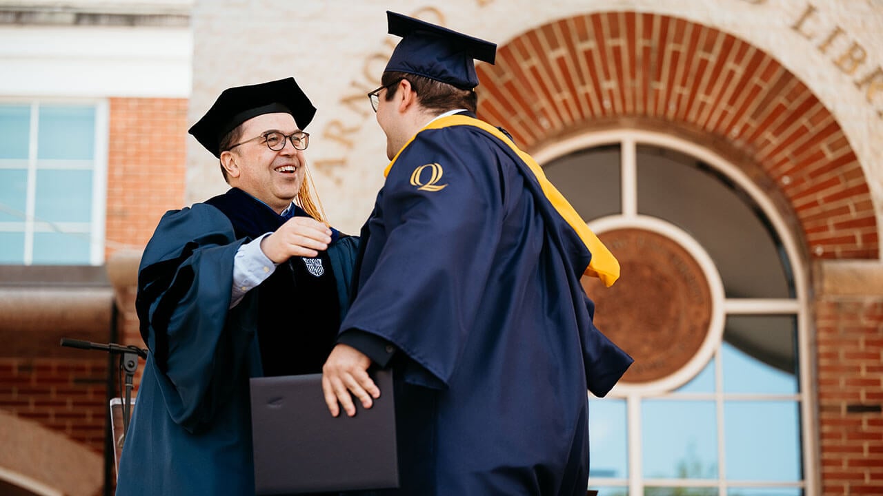 A graduate going in for a hug after getting their diploma