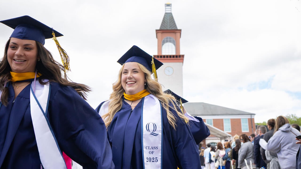 Two students smile as they exit commencement.