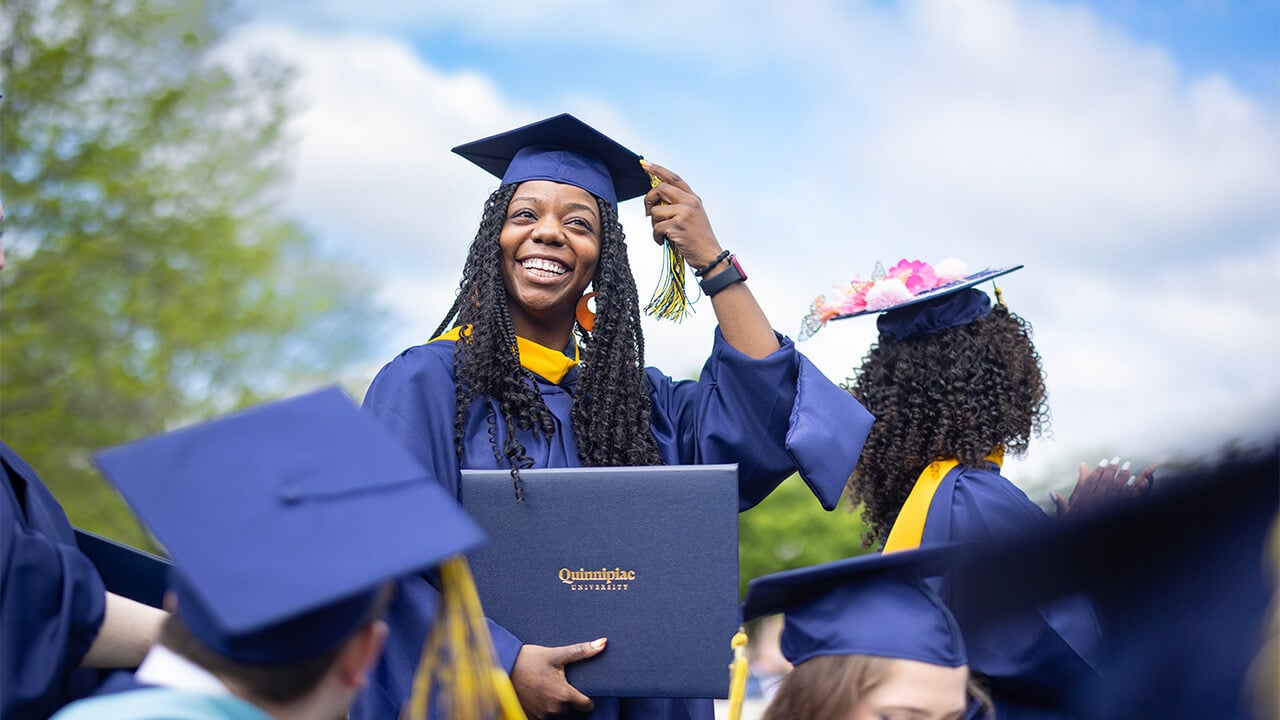 Student holding diploma moves tassel.