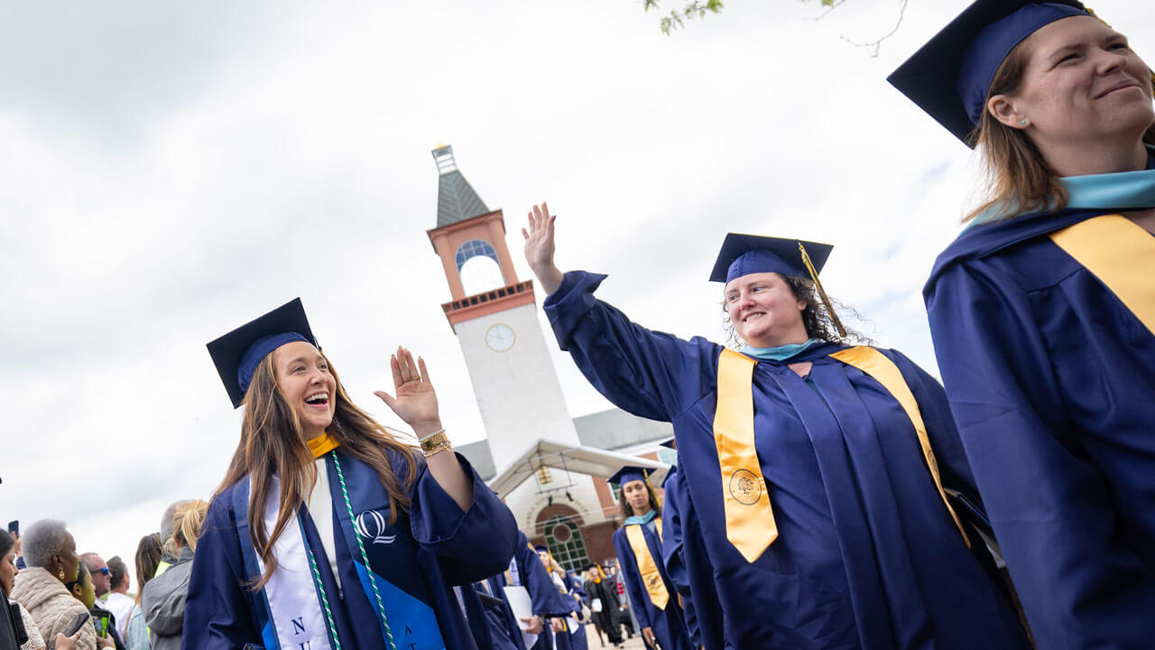 Graduates reach their hands up to high-five as they exit commencement.