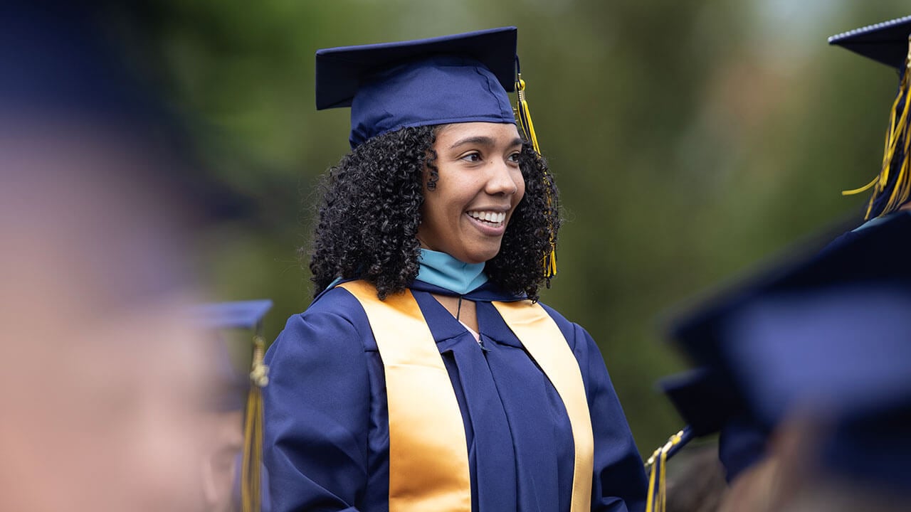 graduate smiles standing out from crowd