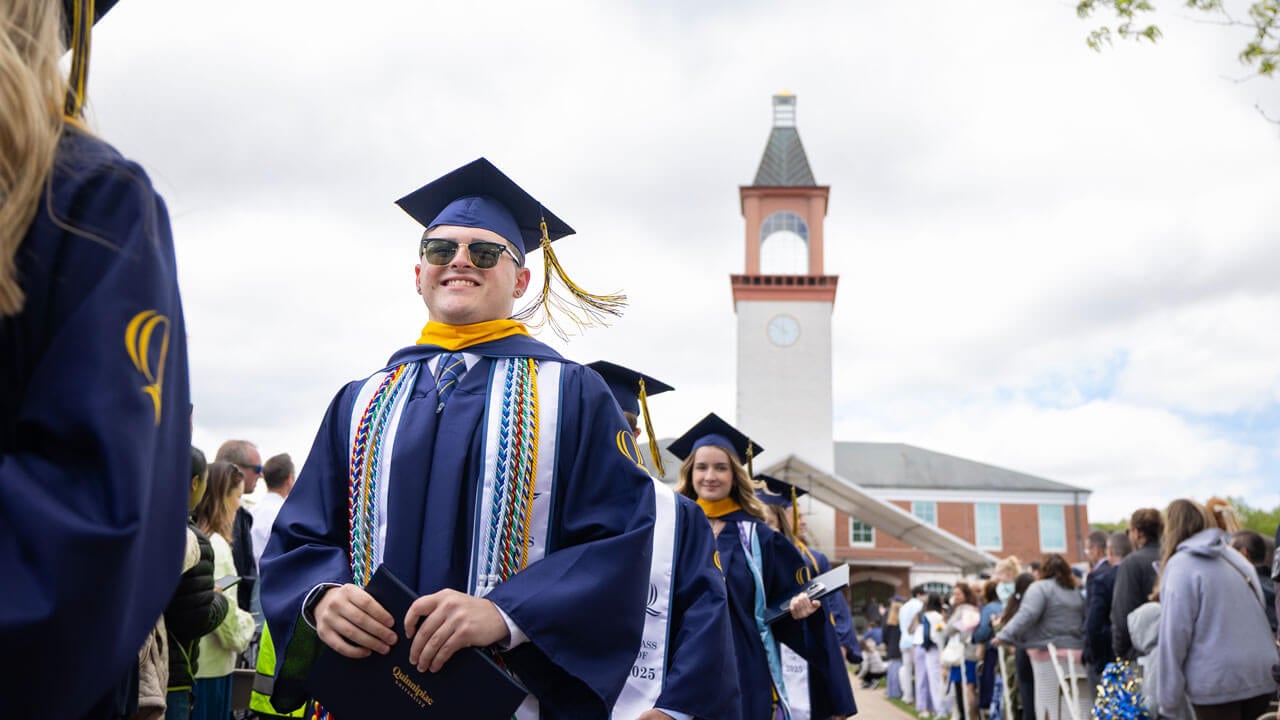 Graduate smiles as they exit commencement.