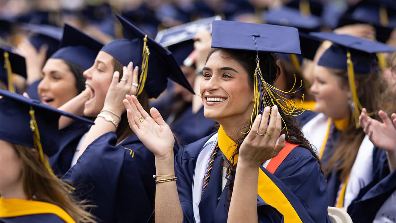 Student smiles in crowd at commencement.
