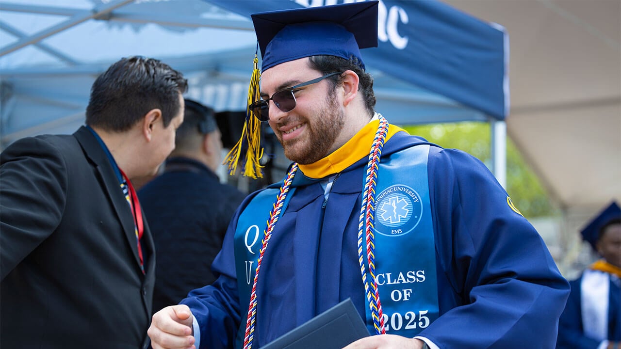 Male student in cap and gown with diploma.