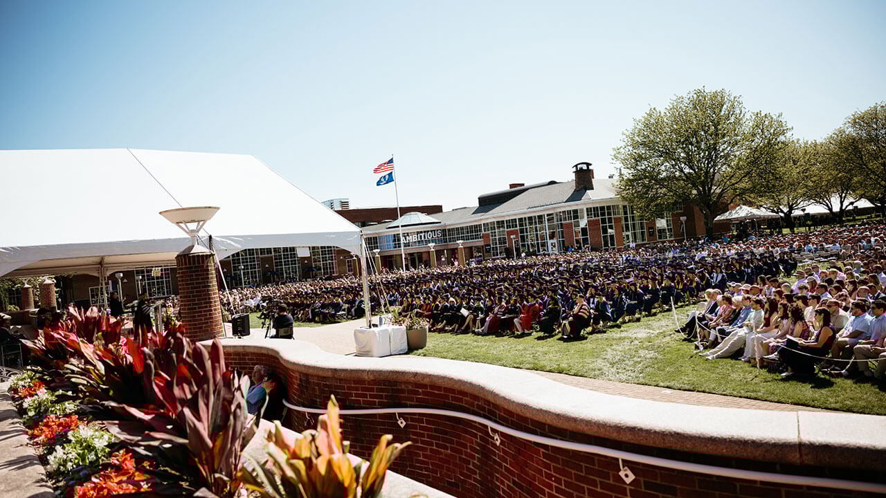 A wide angle photo of health sciences grads sitting on the quad