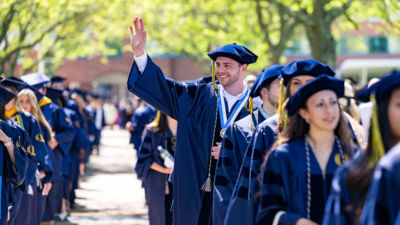A graduate waving towards the crowd