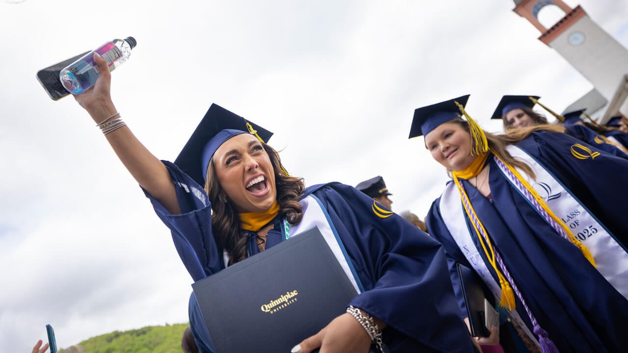 Graduate raises their hand in celebration as they exit commencement.