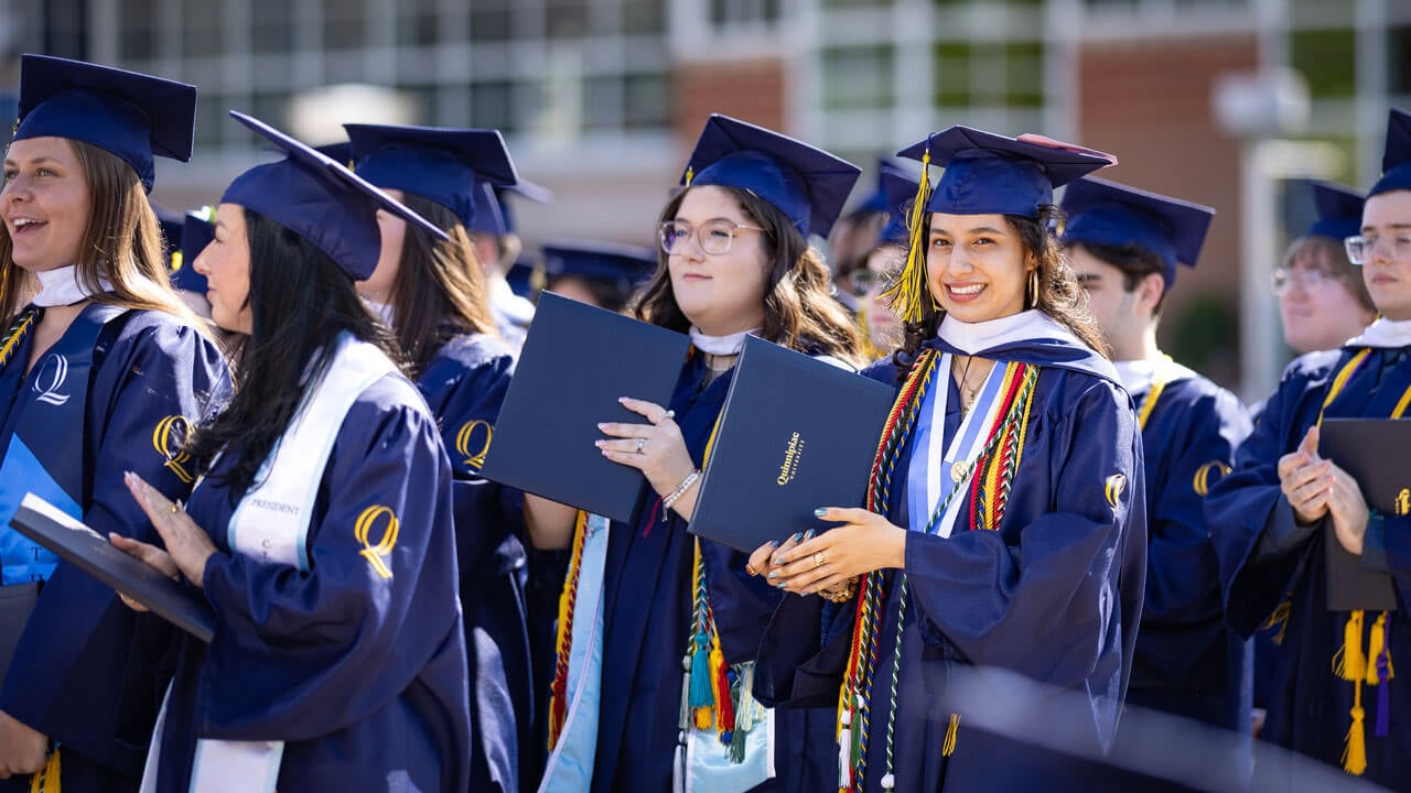 A crowd of graduates clap and smile.