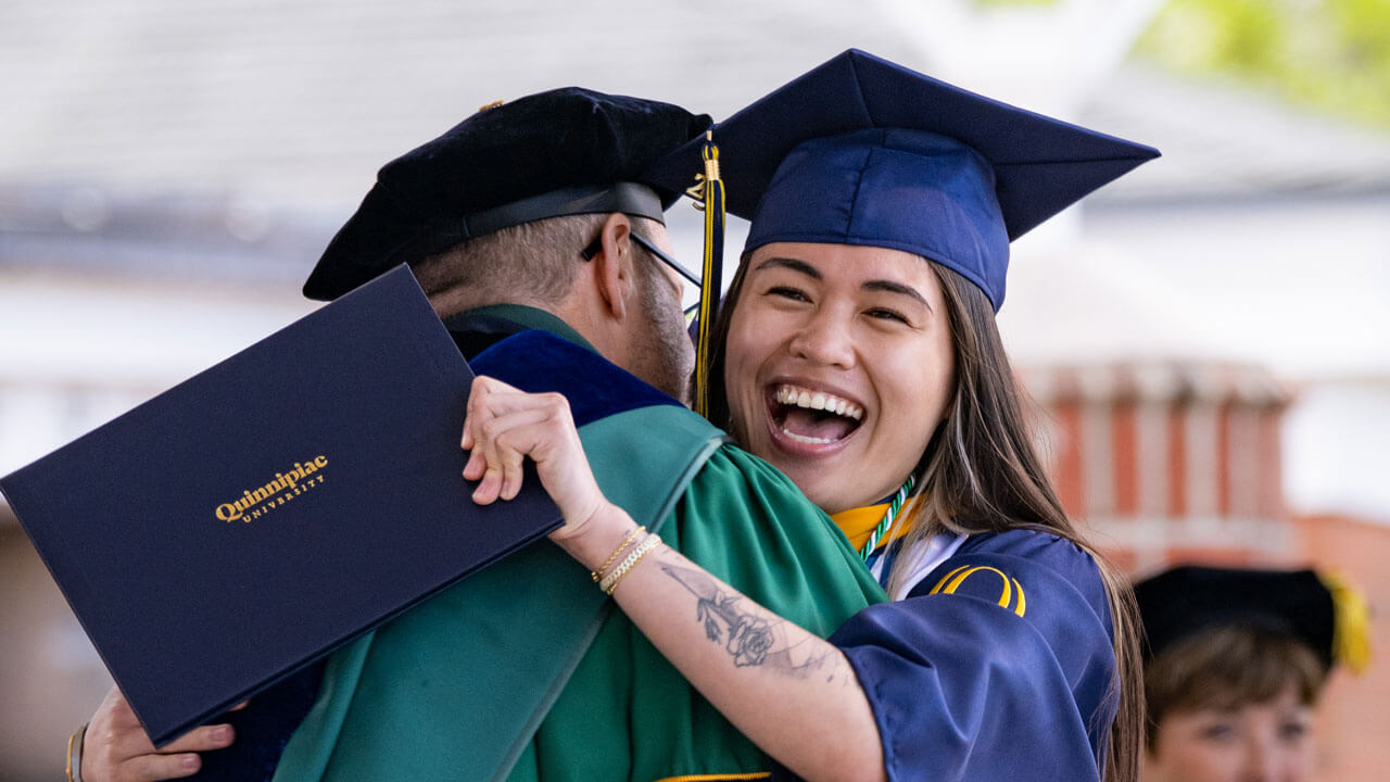 Graduate enthusiastically hugs a University official