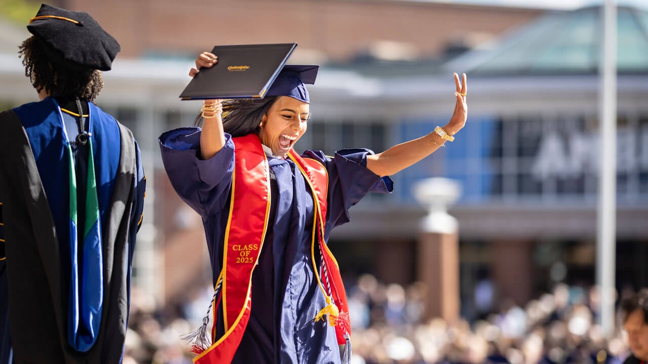 Graduate cheers holding their diploma as they exit the commencement stage.
