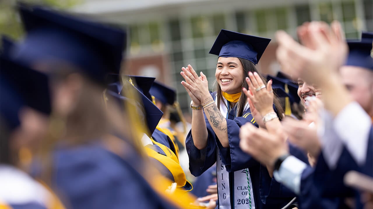 School of Nursing graduate clapping in crowd.
