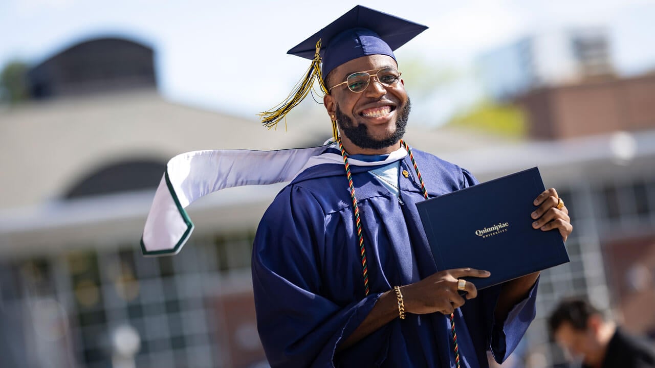 Graduate smiles with their diploma.