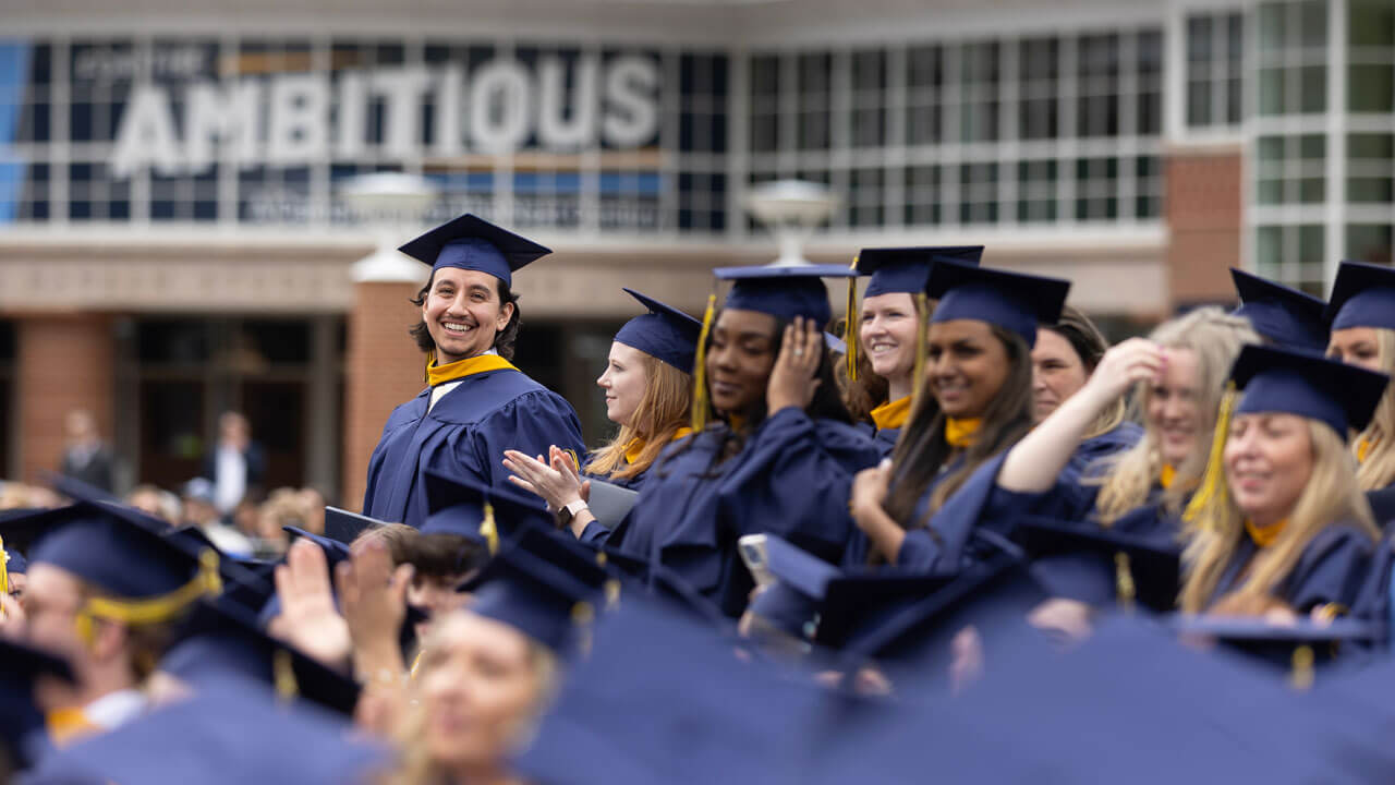 Graduates stand as they move their tassels