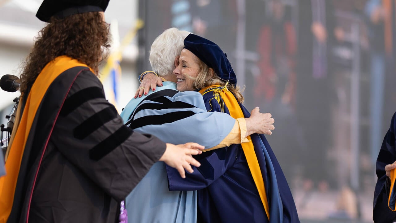 Graduate hugs University official