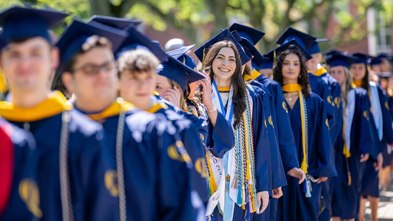 A line of graduates smiling into the distance