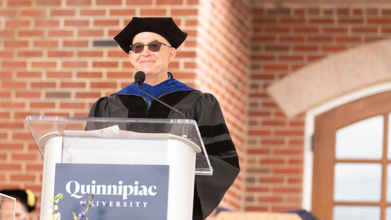 Dean Matthew O'Connor speaks at a podium at the library steps