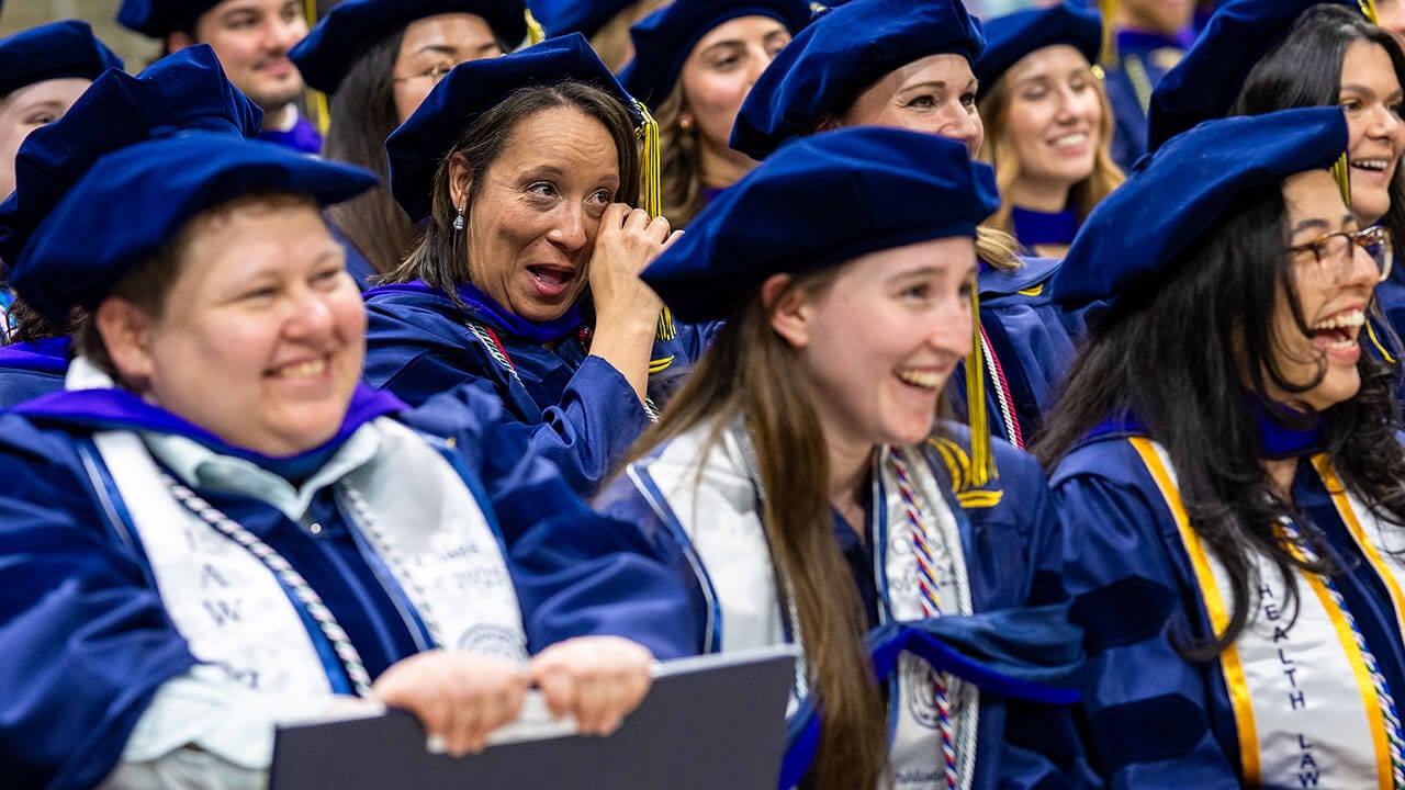 Student wipes tears in a crowd of Graduates.