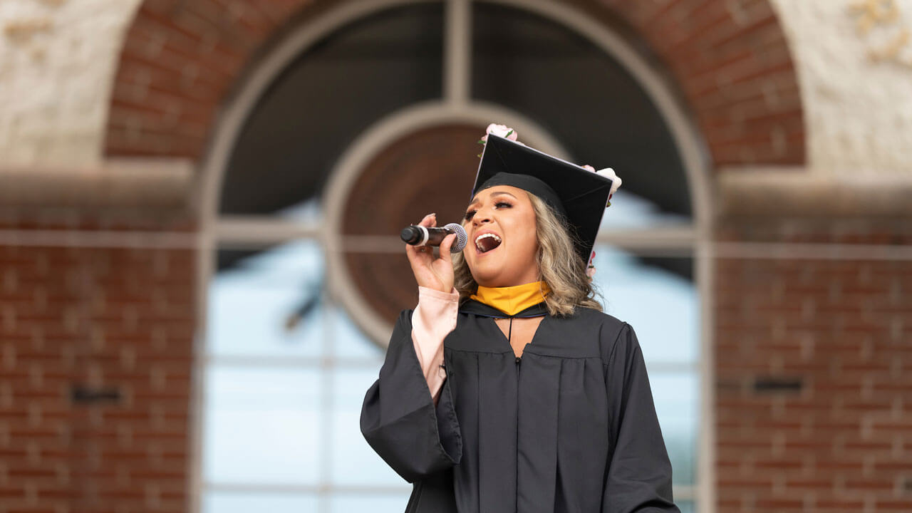 Taina Echevarria sings the national anthem in front of the Quinnipiac library