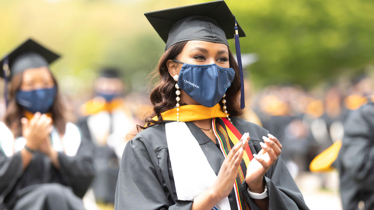 A graduate claps from her seat during Commencement