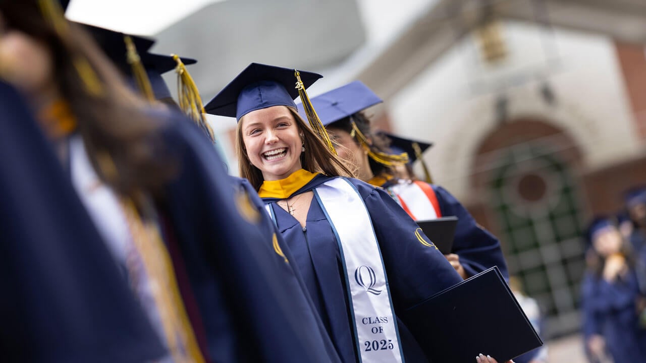 Graduate smiles while walking in procession
