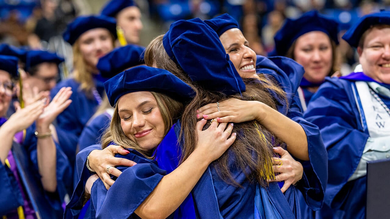 Two graduates hug.