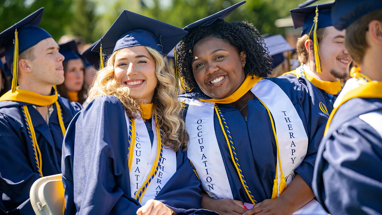 Two occupational therapy grads smile together