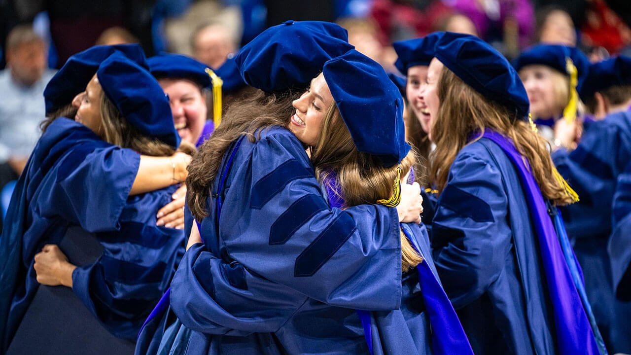 Two graduates hug each other after graduating