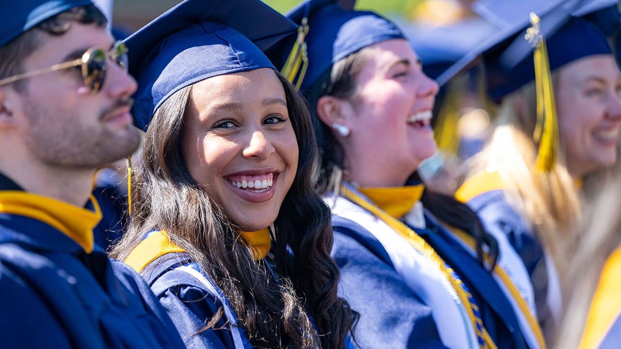 A happy graduate smiles over their shoulder