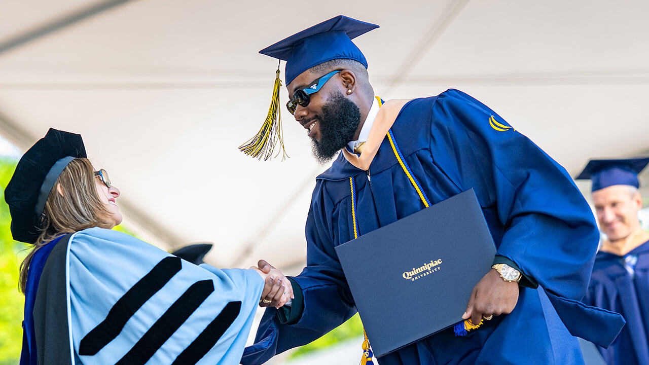 A student shaking hands with Dean Holly Raider