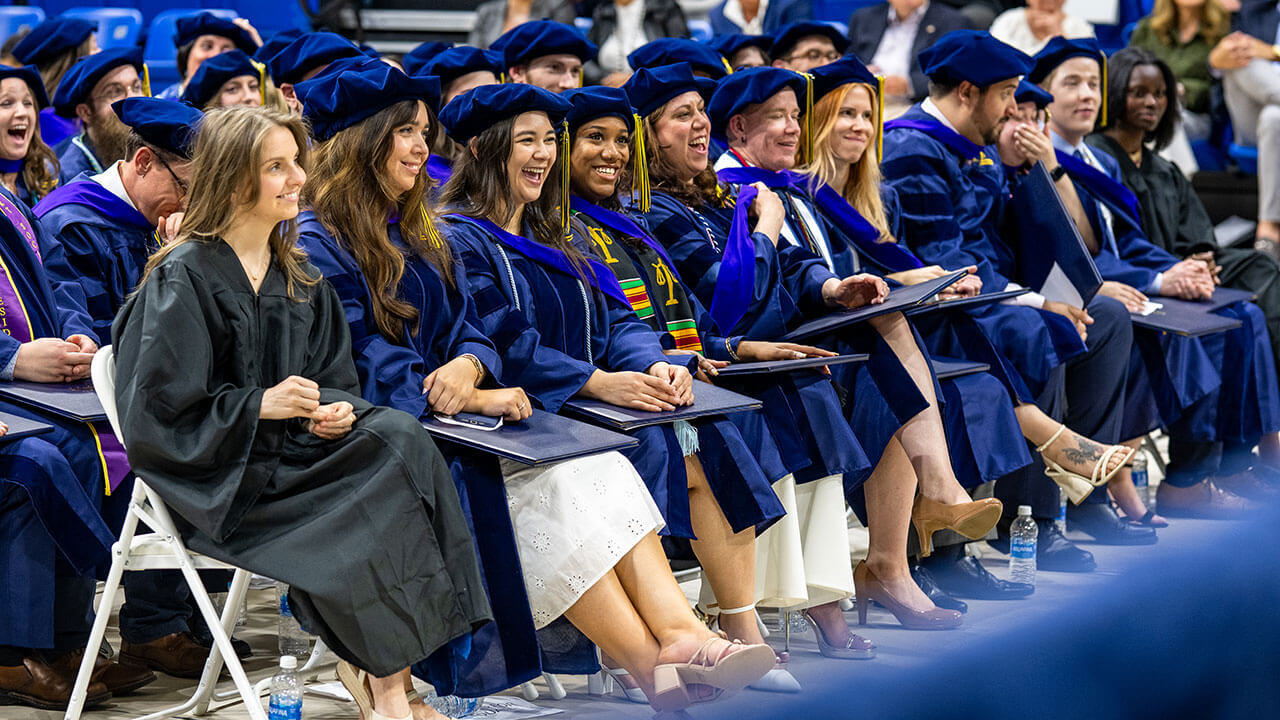 Graduates in the front row smile in the crowd